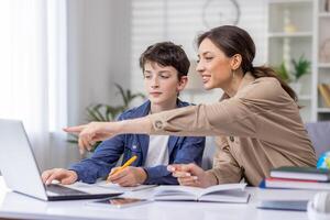 mãe e filho estudando juntos sentado às escrivaninha às casa dentro vivo sala, Garoto e mulher tutor ensino às lar, fazendo dever de casa junto. foto