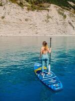 pode 15, 2021. anapa, Rússia. desportivo mulher em ficar de pé acima remo borda às azul mar. surfista mulher em sup borda dentro verão mar. aéreo Visão foto