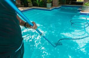 homem limpeza natação piscina com sucção mangueira. pessoa limpeza uma natação piscina com uma vácuo mangueira foto