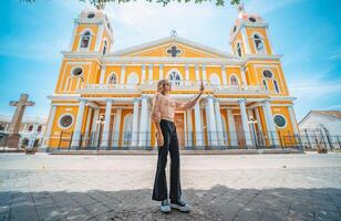 lindo turista levando uma selfie em a rua do a catedral dentro granada, Nicarágua jovem mulher viajante levando uma selfie dentro uma público quadrado dentro frente do uma catedral foto
