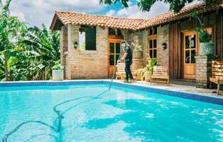 manutenção e limpeza do casa natação piscina com vácuo sucção mangueira. masculino trabalhador limpeza uma lindo natação piscina com vácuo sucção mangueira foto