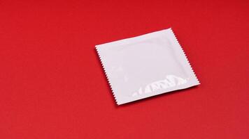 Fechado branco preservativo pacote em vermelho fundo com cópia de espaço foto