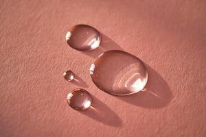 lindo volumétrico gotas do Cosmético produtos em uma Rosa fundo. foto