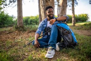 jovem caminhante verificação a Tempo enquanto goza em repouso dentro natureza foto