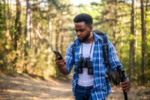preocupado caminhante obteve perdido e ele é usando uma telefone para encontrar certo direção enquanto caminhada dentro a natureza foto
