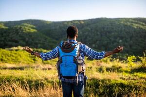 feliz homem caminhante com braços elevado goza dentro a natureza. foto