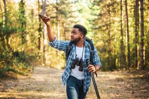 jovem caminhante é procurando sinal para Móvel telefone dentro natureza foto