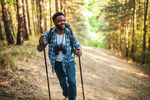 jovem homem goza caminhada dentro natureza. foto