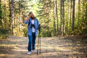 jovem homem é cansado do caminhada enquanto caminhando dentro a natureza. foto