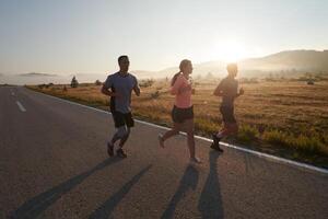 uma grupo do amigos, atletas, e corredores abraço a cedo manhã horas Como elas corre através a enevoado alvorecer, energizado de a Aumentar Sol e cercado de a tranquilo beleza do natureza foto