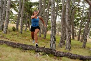 destemido mulher conquistando de madeira obstáculos dentro a perigoso floresta terreno. foto