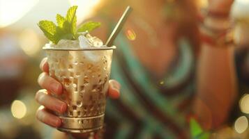 uma refrescante gelado hortelã julep coquetel dentro mão, capturando a essência do verão felicidade às dourado hora foto