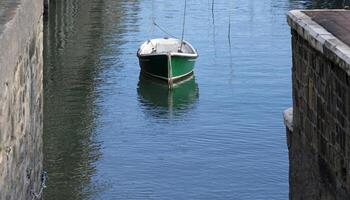 solitário verde barco dentro a calma águas do uma Porto foto
