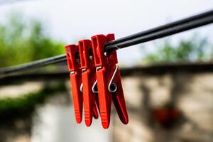 três vermelho prendedores de roupa em uma varal de roupas foto