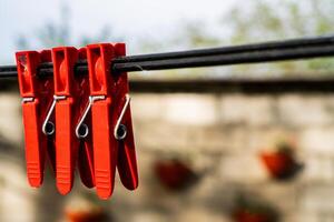 três vermelho prendedores de roupa em uma varal de roupas foto