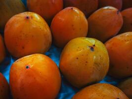 fresco caquis dentro supermercado em a prateleira, fruta loja, fechar acima. caixa com quarto caquis para venda dentro supermercado. ameixa foto