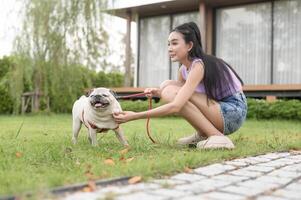 feliz ásia mulher jogando com fofa inteligente pug cachorro cachorro dentro a quintal foto