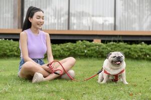 feliz ásia mulher jogando com fofa inteligente pug cachorro cachorro dentro a quintal foto