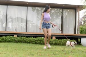 feliz ásia mulher jogando com fofa inteligente pug cachorro cachorro dentro a quintal foto