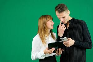 homem e mulher com aparelhos tábua telefone dentro mãos em verde fundo falando rir segurando encontro Aprendendo para trabalhos em Internet paquera relacionamentos paquera casal resolução questão positivo emoções foto