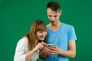 cenário do uma jovem casal assistindo uma engraçado em Móvel telefone, posando em isolado fundo foto
