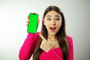 menina telefone chromakey deleite uma mulher dentro uma Rosa suéter com multicolorido manicure grandes cabelo é feliz mostrando dela telefone ela tem azul olhos ela é feliz publicidade estava olhando para o que ela encontrado foto