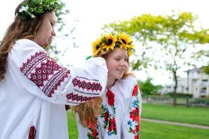 trança russo tranças uma jovem menina dentro a bordado camisa do uma tradicional ucraniano camisa tece tranças para amigo debaixo guirlanda sentar dentro parque gastar agradável Tempo ao ar livre Paz Paz Paz dentro Ucrânia foto