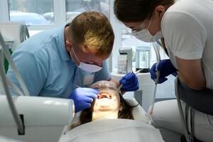 Mais recentes tecnologia limpeza e branqueamento dentes enfermeira e médico tratando dentes do fêmea paciente adolescente. Mais recentes dispositivo dentro uma dental escritório dentro uma clínica levando Cuidado do dentes Branca de Neve sorrir foto