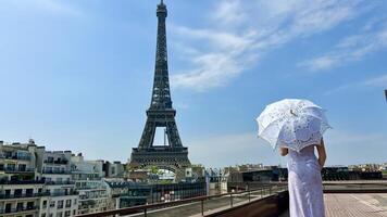 uma lindo jovem menina dentro uma verão vestir carrinhos contra a pano de fundo do a eiffel torre com uma renda guarda-chuva, ela elevado dela mão e Como E se levando fora lá é uma Lugar, colocar para publicidade viagem agência foto