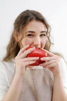 engraçado alegre adolescente menina jovem mulher morder vermelho Pimenta saudável comendo delicioso Comida cozinhando salada Atenciosamente astuto Veja sorrir lindo dentes Castanho cabelo avental cozinha fechar-se delicado manicure saúde foto