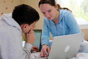 resolver problema do computador portátil adolescentes Garoto menina inclinado resolução problemas fazendo dever de casa crianças Aprendendo juntos conectados Aprendendo Inglês curso Socorro com dever de casa amizade relação sentar às casa em sofá foto