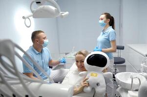 dental clínica Diversão alegria feliz paciente suave brinquedo mulher médico e assistente comunicar resolução problema mulher sorrisos dentro quadro, Armação o mais novo tecnologia espaço para texto venha para nosso odontologia tudo para pessoas foto