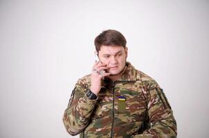 sério conversação em telefone. militares homem enrugado testa importante mensagem dados transmissão guerra inscrição armado forças do Ucrânia em Jaqueta militares homem camuflar exército uniforme chamando foto