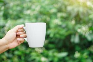 fechar acima mão aguarde cerâmico caneca, ao ar livre natureza fundo. conceito, relaxar Tempo com favorito bebida.take uma pausa com café, quente chocolate ou chá. reutilizável e lavável copo. eco amigáveis estilo de vida. foto