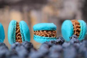 mirtilo Macarrão bagas espalhados em a mesa perto delicioso doces caramelo o preenchimento do azul Macarrão borrado foco espaço para texto publicidade cartão postal festa convite delicioso doce sobremesa foto