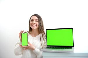 mulher assistindo verde tela computador portátil lindo jovem menina dentro branco suéter mostra computador portátil com chromakey anuncia uma produtos Boa apresentação alegria ganhar venda agradável positivo emoções em uma branco fundo foto