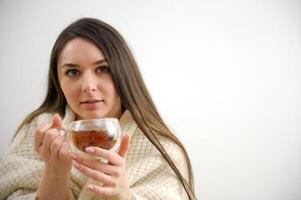 lindo menina a Loiras com uma chá caneca dentro mãos foto