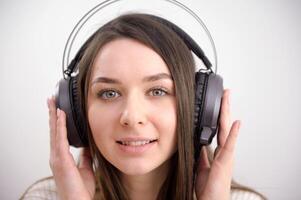a menina dentro fones de ouvido jovem mulher ouvindo dela favorito canções dentro fones de ouvido olhando engraçado em isolado branco fundo foto