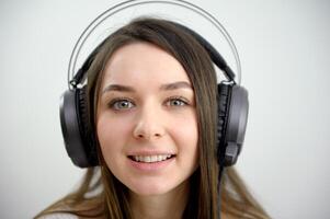 face do uma jovem menina dentro fones de ouvido luminoso olhos lindo sorrir fechar-se em branco fundo grande fones de ouvido aluna aluna conectados conferência Treinamento Inglês língua cursos ouvindo compreensão foto