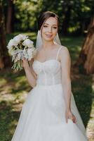 uma mulher dentro uma branco vestir é segurando uma ramalhete do flores foto