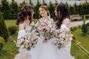 três mulheres estão segurando buquês do flores e posando para uma cenário foto