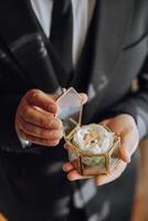 uma homem é segurando uma pequeno caixa com uma branco flor dentro foto