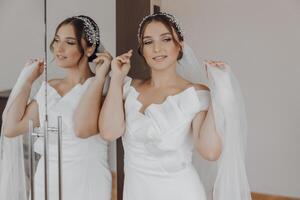 uma mulher é obtendo pronto para dela casamento, colocando em dela véu foto