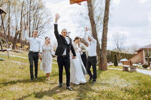 uma grupo do pessoas estão a comemorar uma Casamento dentro uma parque foto