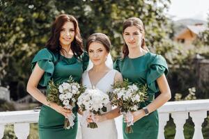 três mulheres dentro verde vestidos estão segurando buquês do flores foto