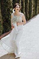 uma mulher dentro uma branco vestir é caminhando baixa uma caminho com uma ramalhete do flores dentro dela foto