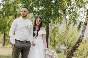 uma homem e mulher estão em pé dentro uma floresta, a homem é vestindo uma branco camisa foto