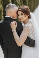 uma homem e mulher estão abraçando cada outro, com a mulher vestindo uma Casamento vestir foto