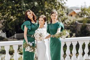 três mulheres dentro verde vestidos estão posando para uma foto com flores