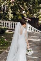 uma mulher dentro uma branco vestir é caminhando baixa uma pedra caminho com uma ramalhete do flores foto